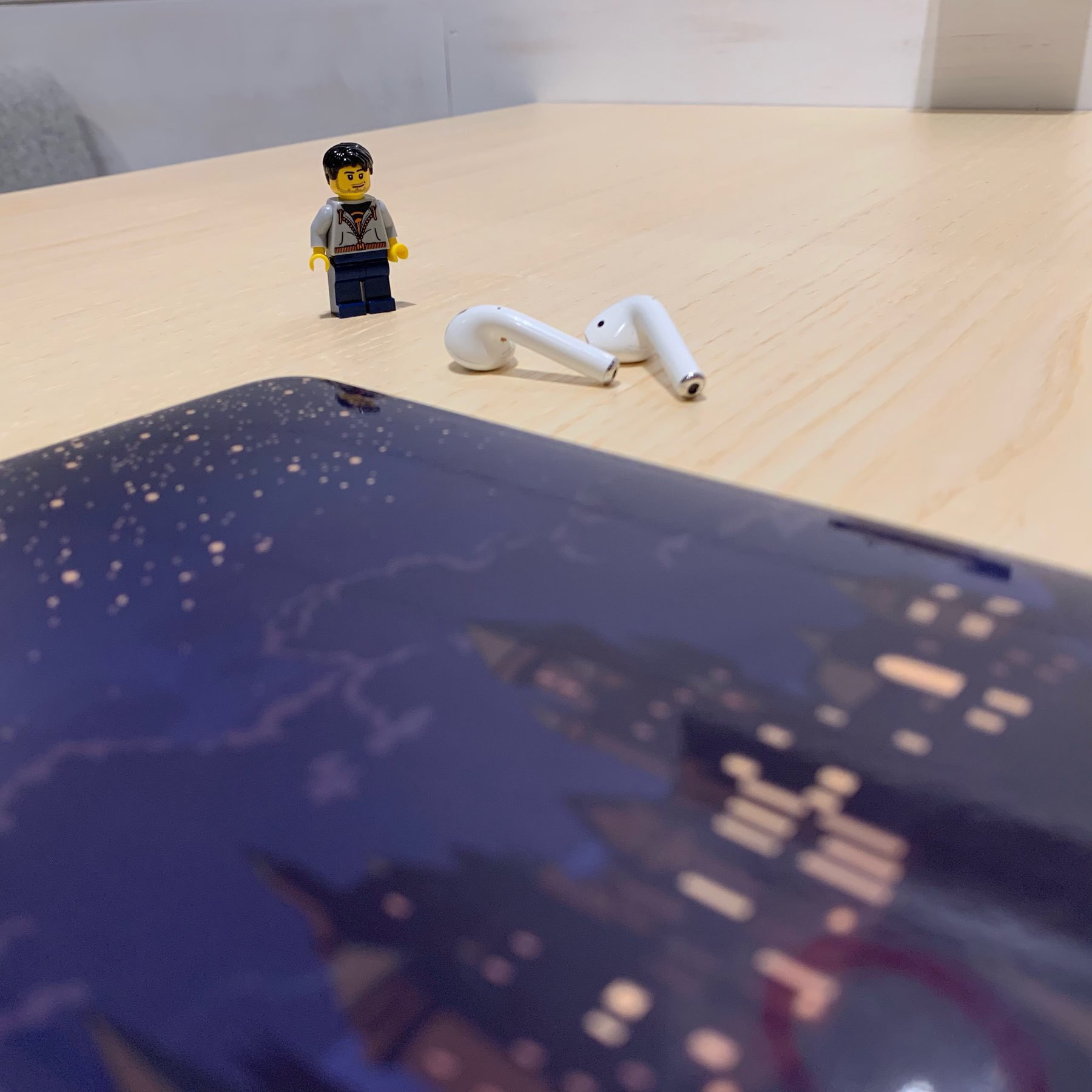 A LEGO minifigure and a pair of airpods next to a Hogwarts-skinned MacBook.