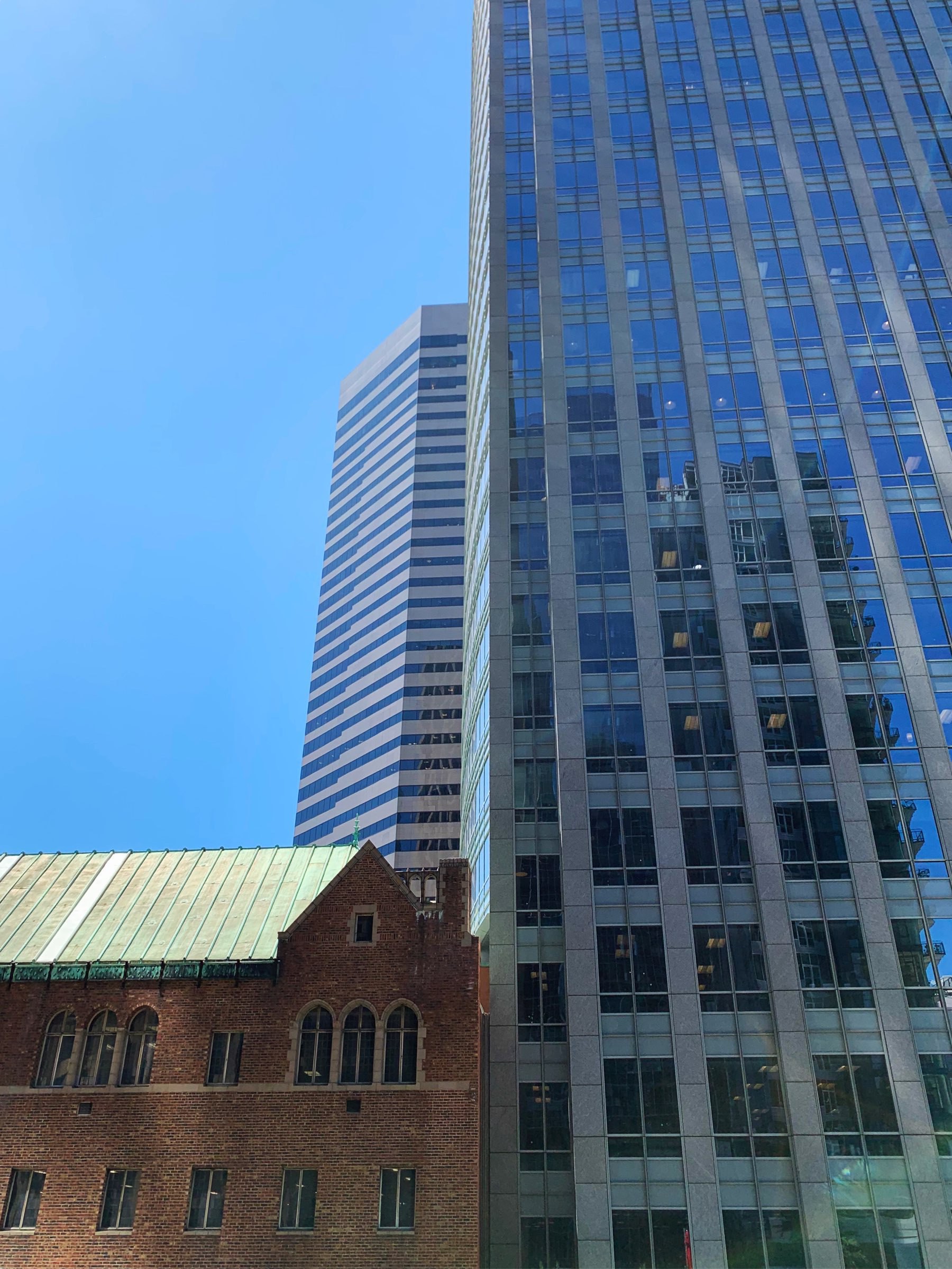 an old brick building next to a very modern glass skyscraper.